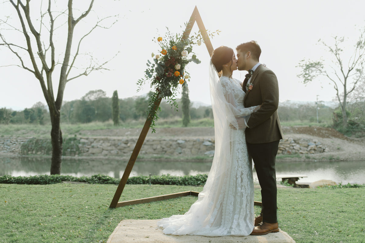 A couple sharing a kiss beside the water at their outdoor ceremony