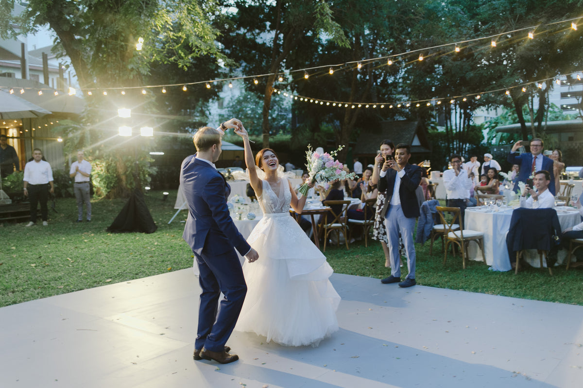 A couple celebrating with their guests in a garden beneath strings of lights